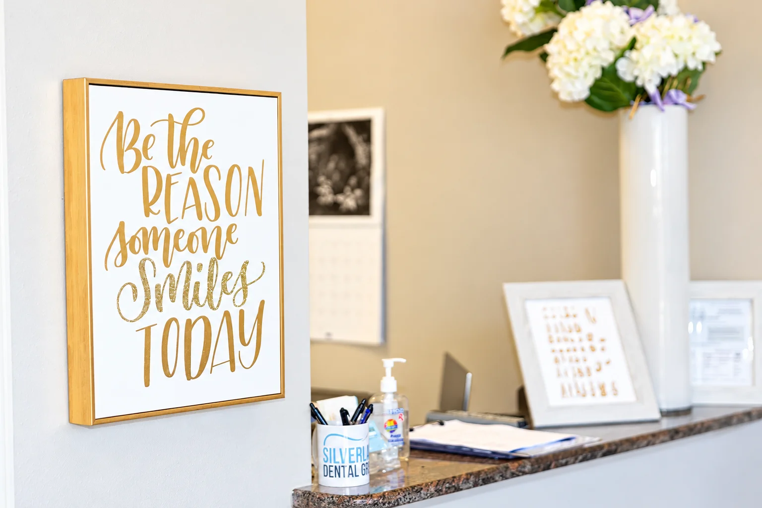 Front desk with flowers and a “Be the reason someone smiles today” sign